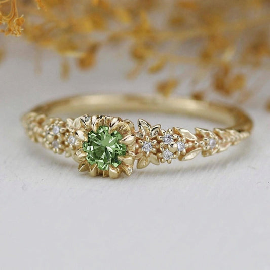 Yellow gold floral engagement ring with a round green sapphire and white diamonds