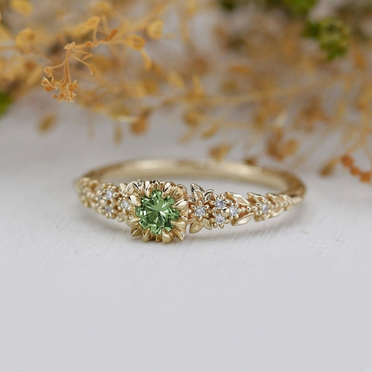 Yellow gold floral engagement ring with a round green sapphire and white diamonds