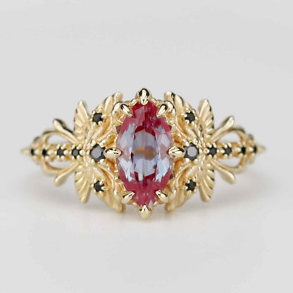 18k yellow gold dragonfly ring featuring a marquise-cut lab alexandrite center stone and black diamond accents on a white background.