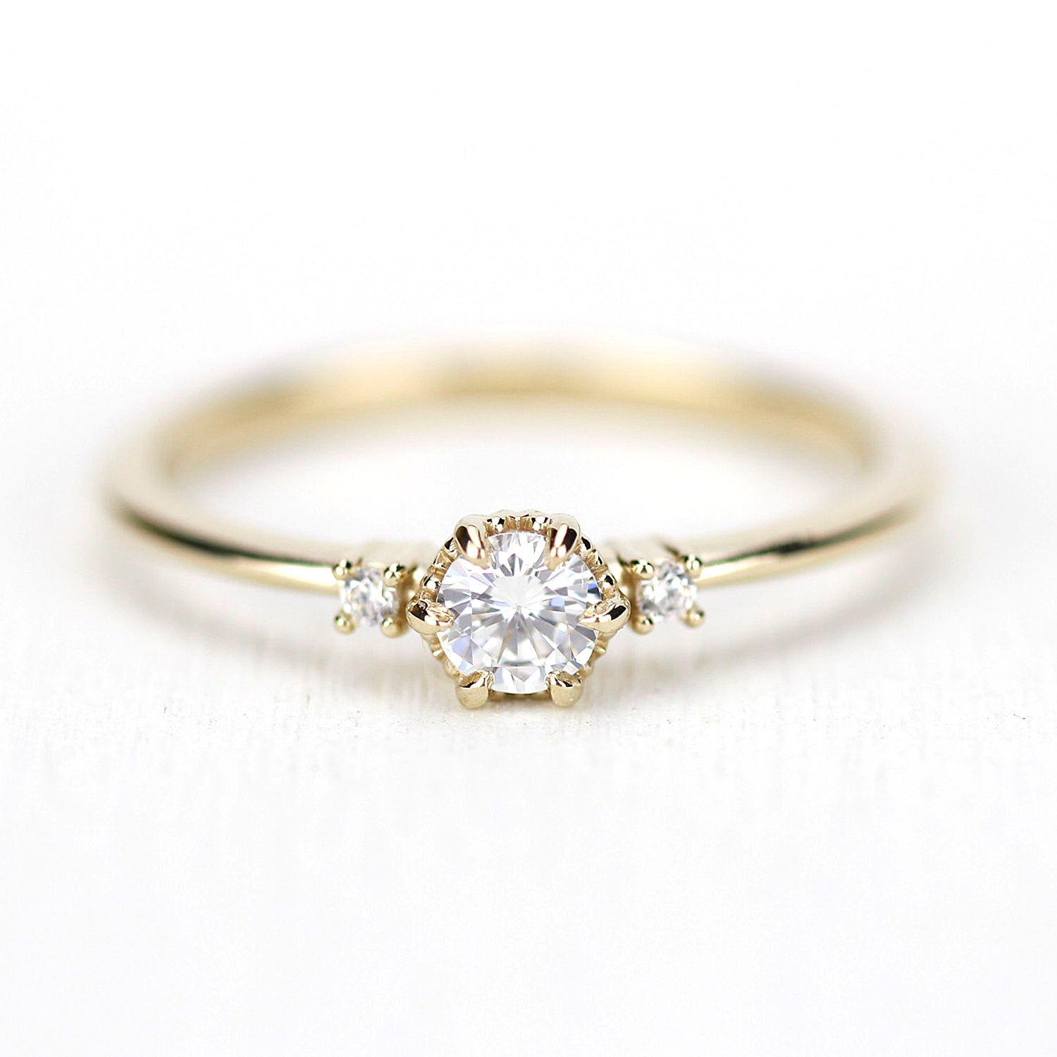 Front view of a three-stone 18k gold ring featuring a 0.2ct round brilliant natural diamond in a crown-style milgrain setting with two side accent diamonds.