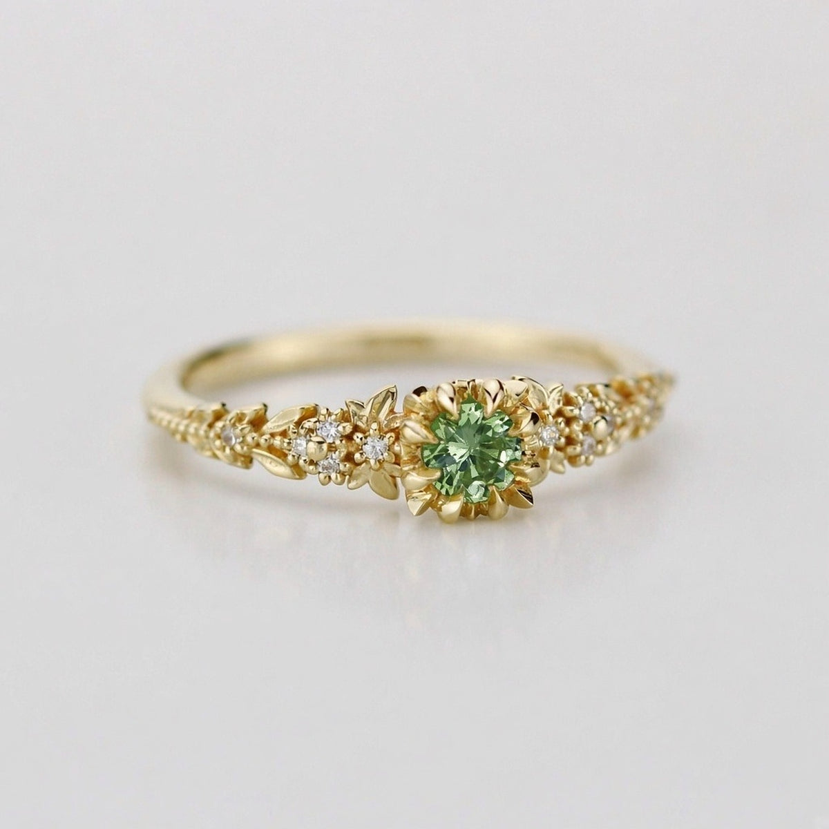 Yellow gold floral engagement ring with a round green sapphire and white diamonds