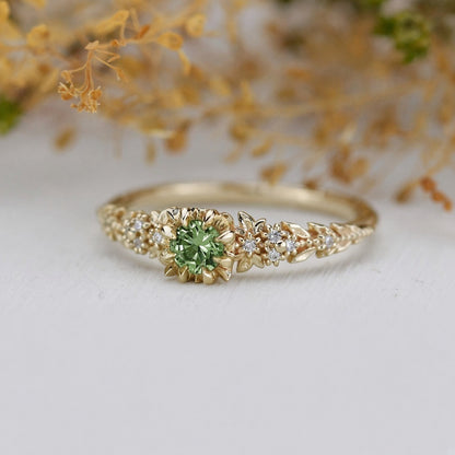 Yellow gold floral engagement ring with a round green sapphire and white diamonds
