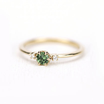 Yellow gold petal ring with a green sapphire, turned toward the left, two diamond side stones