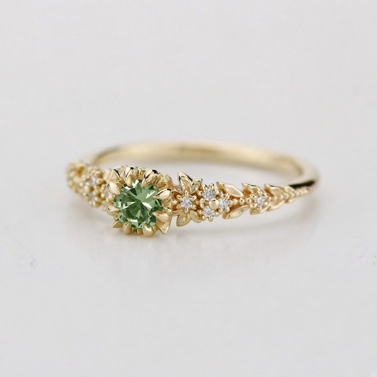 Yellow gold floral engagement ring with a round green sapphire and white diamonds
