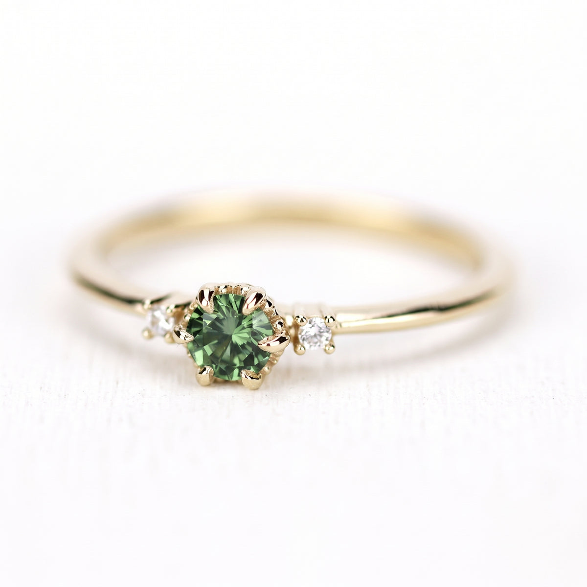 Yellow gold petal ring with a green sapphire, seen from the side, band and prongs visible