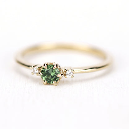 Yellow gold petal ring with a green sapphire, seen from the side, band and prongs visible