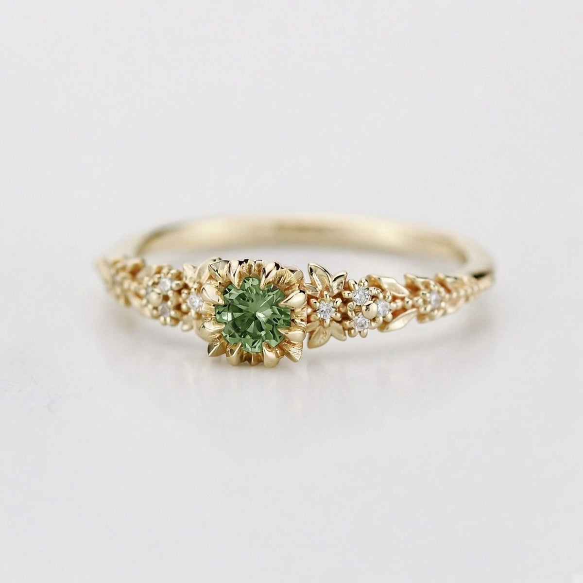 Yellow gold floral engagement ring with a round green sapphire and white diamonds