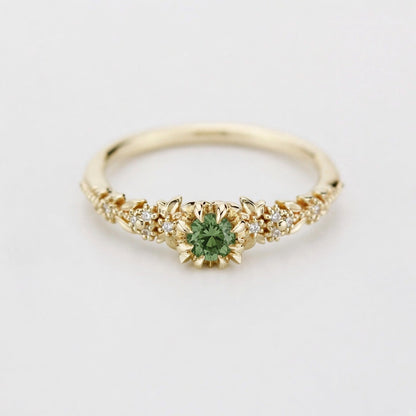 Yellow gold floral engagement ring with a round green sapphire and white diamonds
