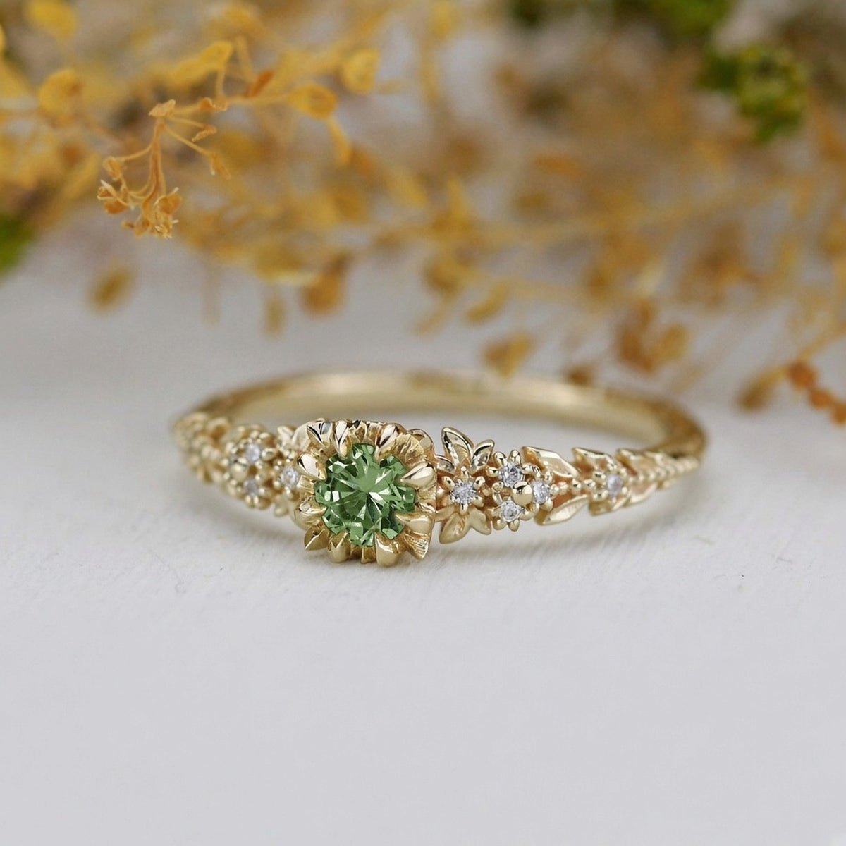 Yellow gold floral engagement ring with a round green sapphire and white diamonds
