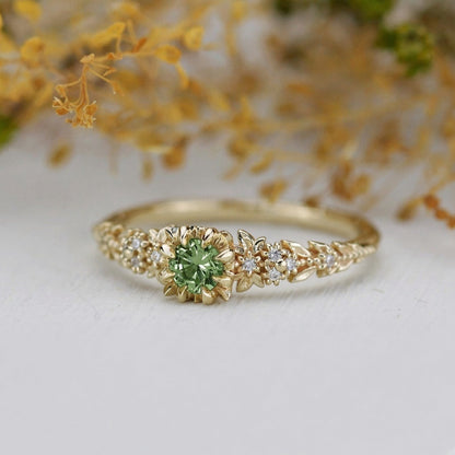 Yellow gold floral engagement ring with a round green sapphire and white diamonds