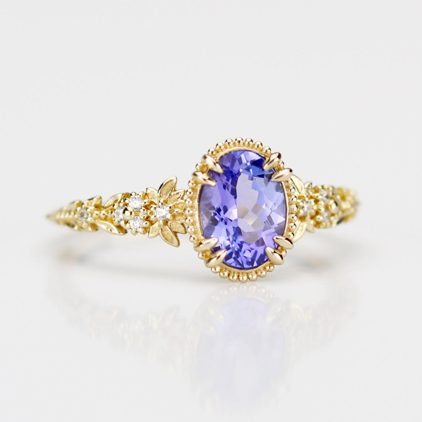 Front view of the Anthea 18k yellow gold ring showcasing a vibrant natural tanzanite and white diamond floral details, 