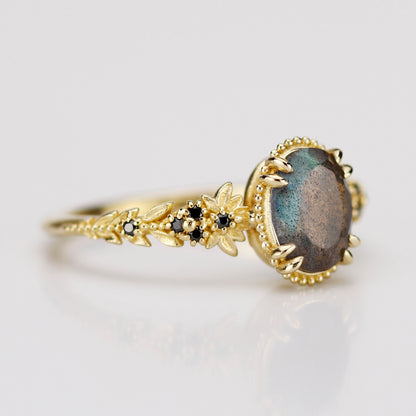 Close-up of the Anthea labradorite ring showing the intricate gold leaf detailing and milgrain bezel setting with genuine black diamond accents.