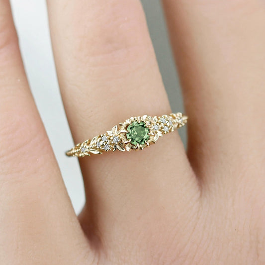 Awen floral ring with a green sapphire and white diamonds, worn on a finger