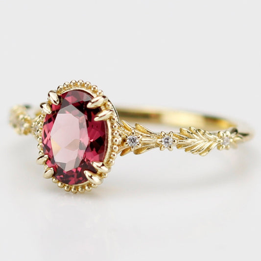 Side view of Rosmaris vintage gold ring featuring a natural oval Rhodolite Garnet gemstone in a milgrain bezel with leaf-shaped botanical band and diamonds.