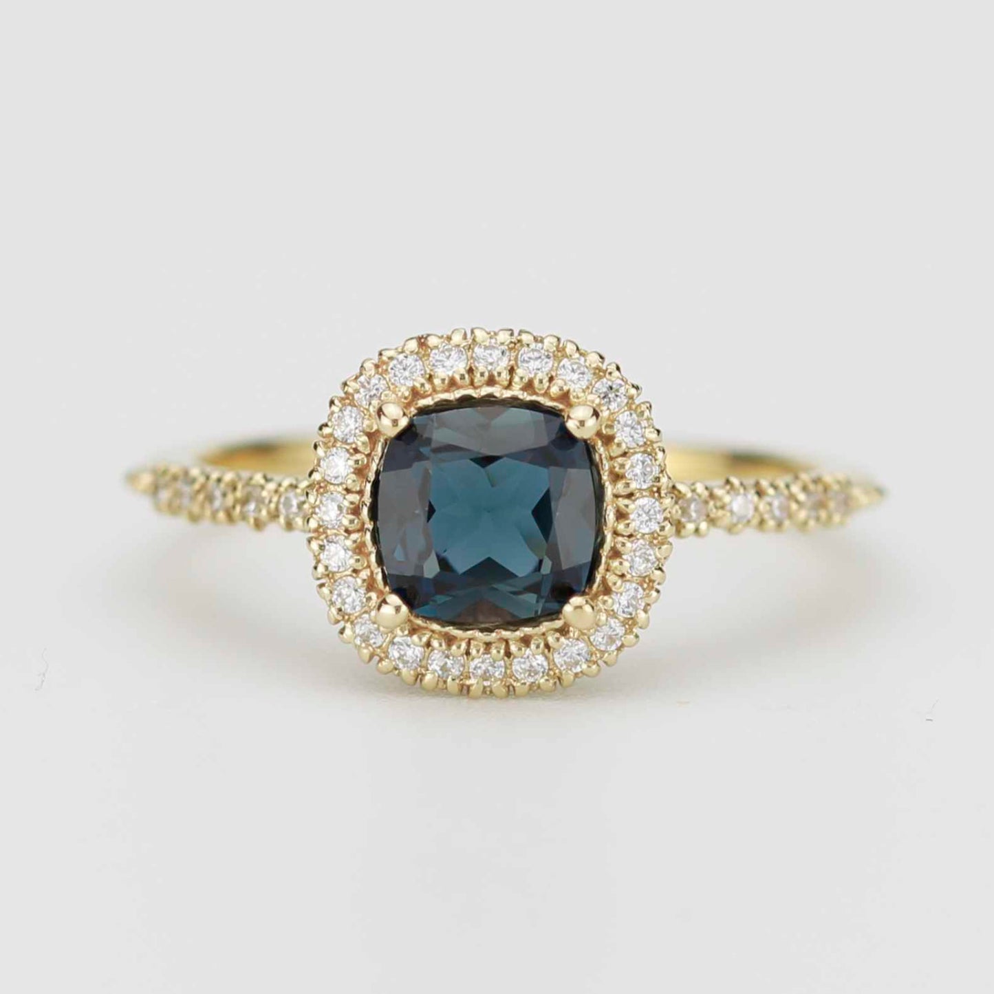 Front view of NOOI Pillow ring in 18k gold featuring a cushion cut London Blue Topaz with a diamond halo and pavé band. 
