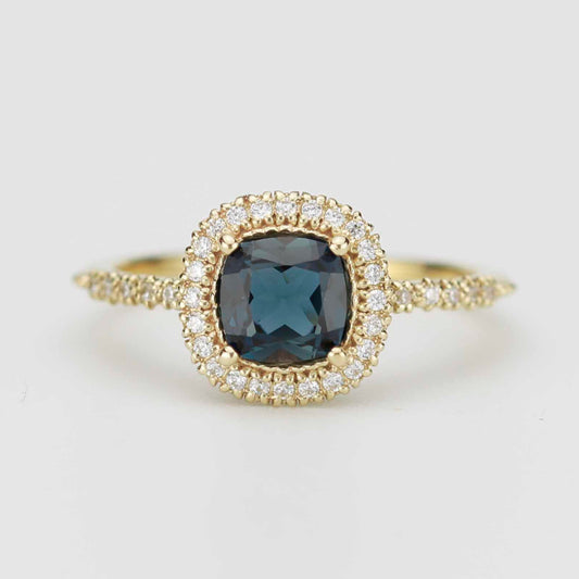 Front view of NOOI Pillow ring in 18k gold featuring a cushion cut London Blue Topaz with a diamond halo and pavé band. 
