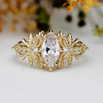 Top-down view of a handcrafted 18k yellow gold dragonfly engagement ring featuring a certified 10x5mm marquise-cut white moissanite center stone. The intricate filigree wings are accented with small natural diamonds, set on a background.