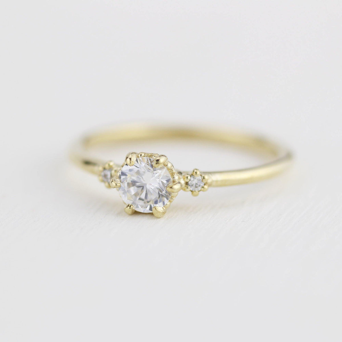 18k gold three stone ring with a round lab grown diamond, angled view