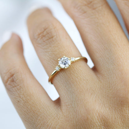 18k gold three stone ring with a round lab grown diamond, worn on the hand, closer