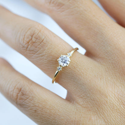 18k gold three stone ring with a round lab grown diamond, worn on the hand, farther view