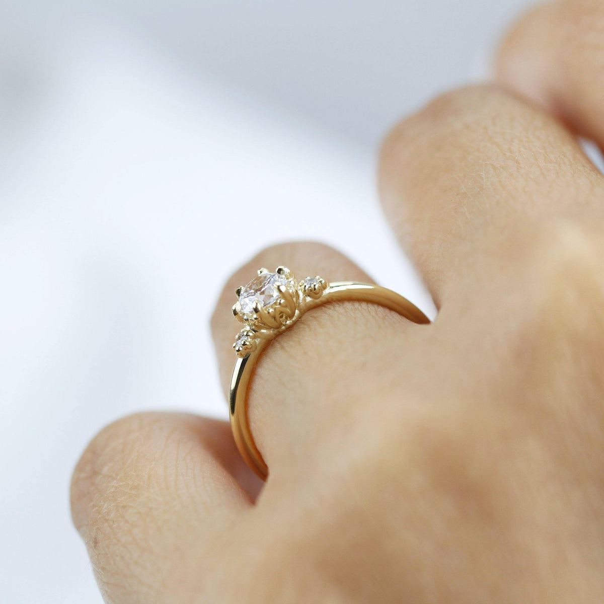 18k gold three stone ring with a round lab grown diamond, worn on the hand, side view