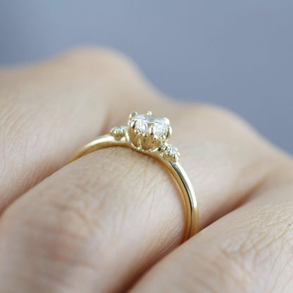 18k gold three stone ring with a round lab grown diamond, worn on the hand, profile