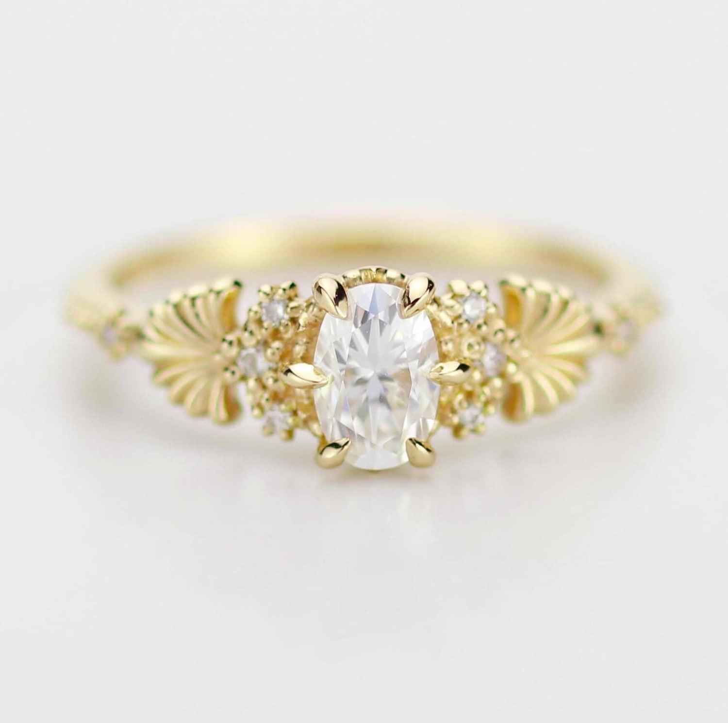 Art Nouveau moissanite ring with natural diamond side stones, set in gold. Vintage-inspired design with oval moissanite center and diamond accents, perfect for engagement or special occasions.