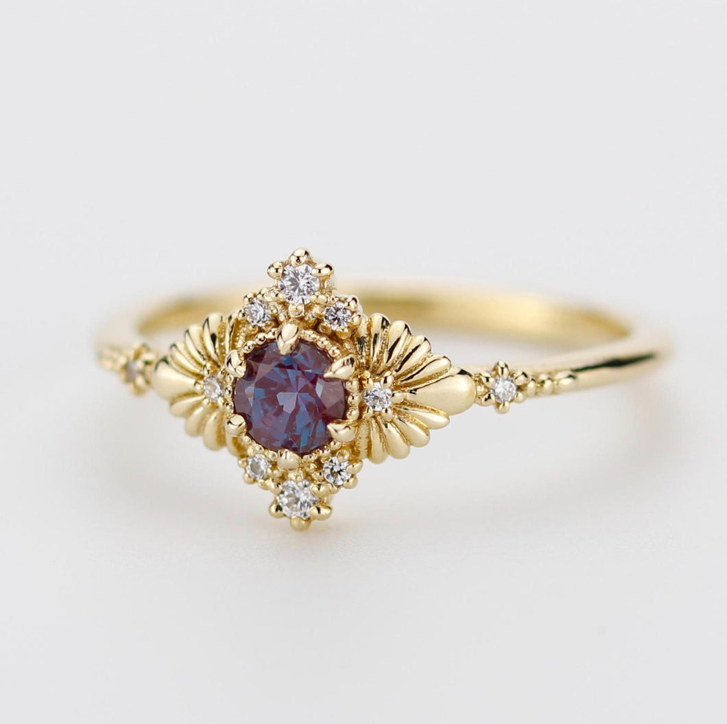 Stunning vintage-inspired ring featuring a lab-created Alexandrite center stone, color-changing from reddish-purple to blue, set in 18k solid gold with natural diamond accents, perfect as a unique engagement ring or statement piece.
