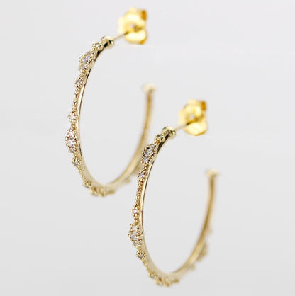 Close-up of elegant 18K solid gold hoop earrings with natural diamond accents and delicate beaded detailing, set against a white background. Luxurious fine jewelry for women, perfect for everyday wear or special occasions.