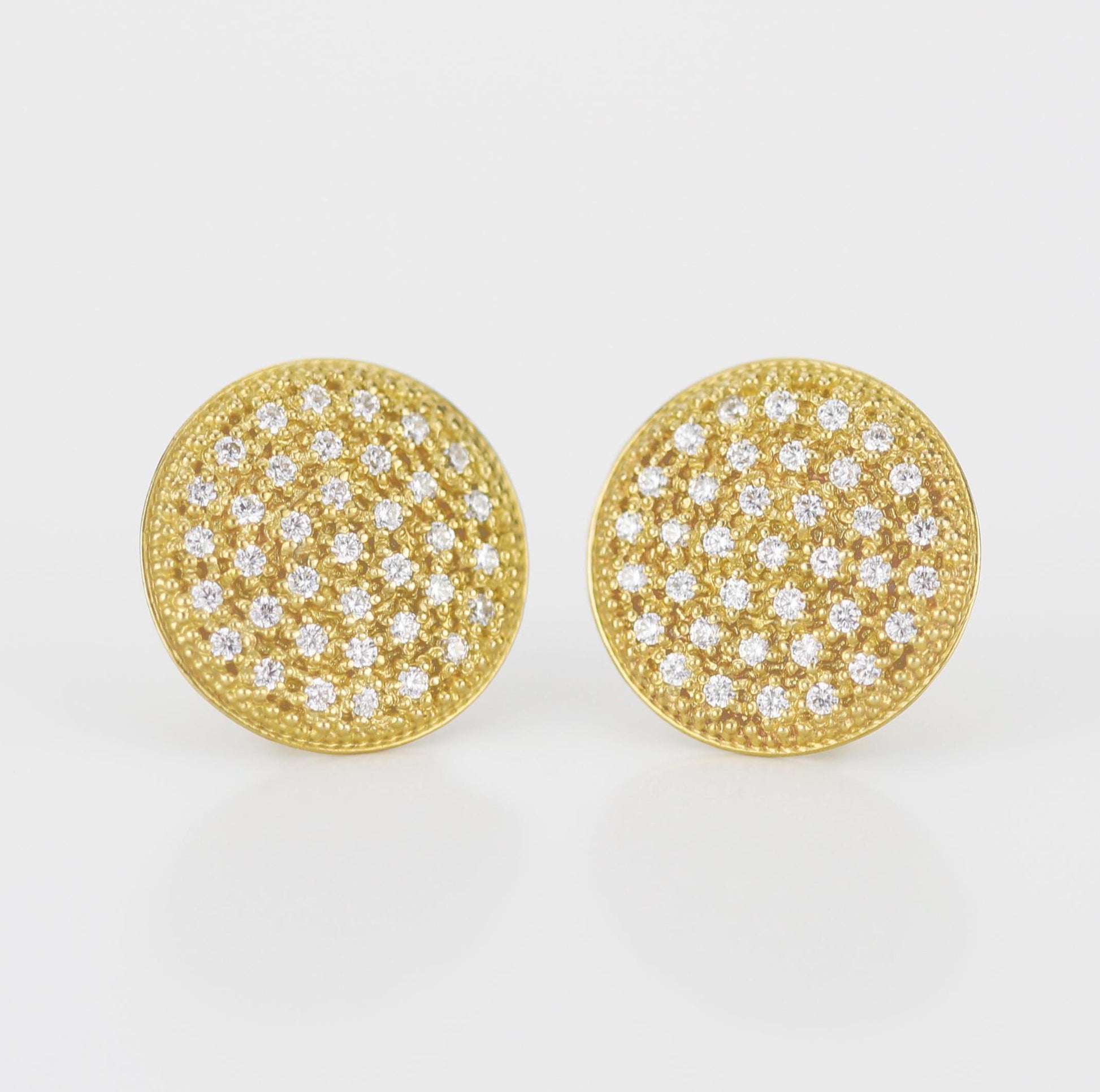 Close-up of elegant 18K solid gold round disk stud earrings, featuring 74 natural 1mm G color VS clarity diamonds in a pave setting, with a butterfly ear back, sparkling against a white background