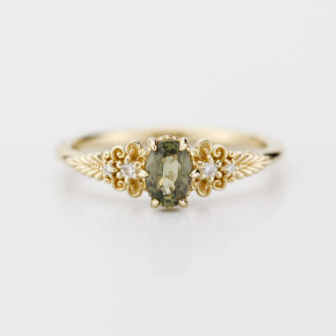 A vintage-inspired 18K gold ring featuring a olive green sapphire, accented with delicate filigree details and natural diamonds, creating an antique-style engagement or heirloom ring.