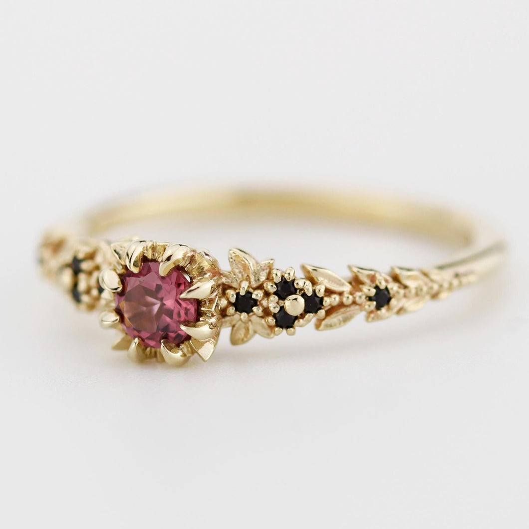 18k gold fantasy-inspired ring featuring a 4mm round rhodolite garnet center stone, flanked by black diamonds and intricate leaf detailing, evoking an ethereal, woodland elvish design