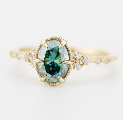 An elegant 8x6 mm teal moissanite gemstone set in an 18k gold band, accented with sparkling diamonds for a refined, luxurious look.