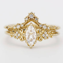 Load image into Gallery viewer, Vintage-inspired marquise moissanite engagement ring with V-shaped diamond wedding band in 18k yellow gold, handcrafted with filigree detailing.