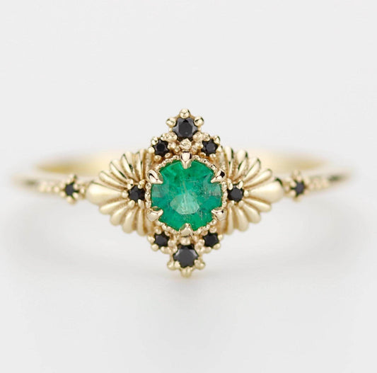 Vintage-inspired 18k solid gold ring featuring a natural emerald center stone and black diamond accents, designed in an elegant Art Deco style. Perfect as an engagement ring or heirloom statement piece.