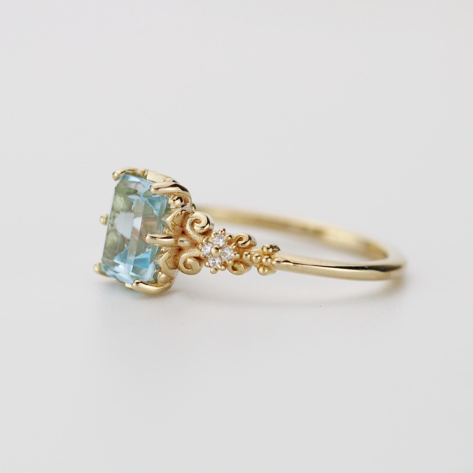 Emerald cut blue gemstone ring set in 18K solid gold with diamond accents and vintage-inspired detailing