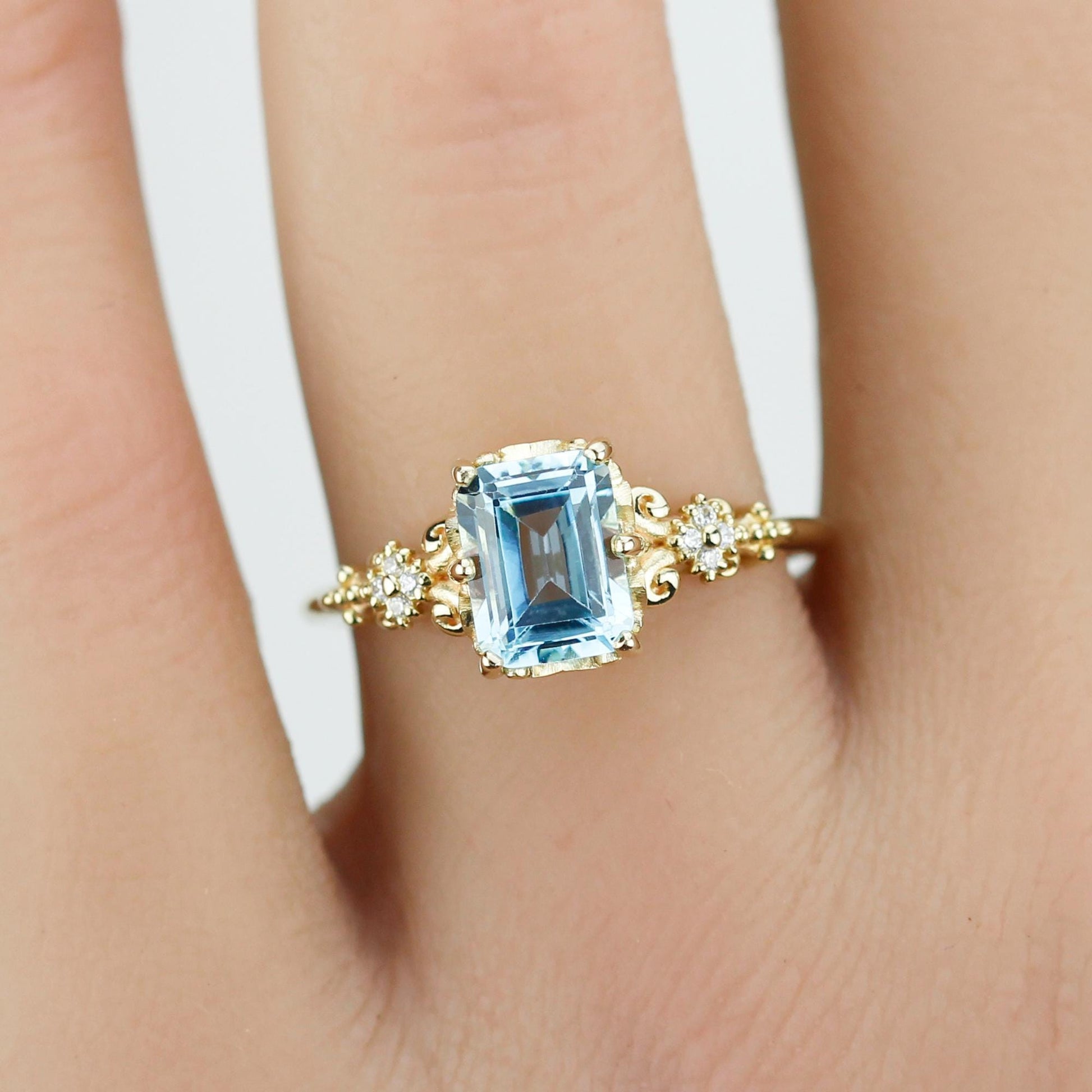 Emerald cut blue gemstone ring set in 18K solid gold with diamond accents and vintage-inspired detailing