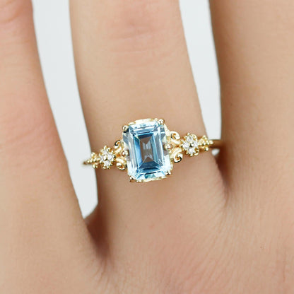 Emerald cut blue gemstone ring set in 18K solid gold with diamond accents and vintage-inspired detailing