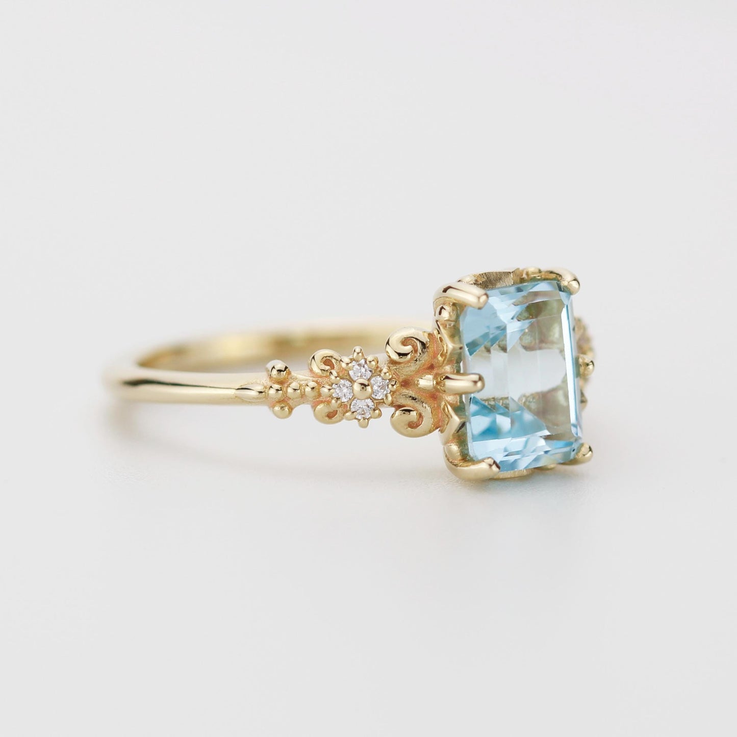 Emerald cut blue gemstone ring set in 18K solid gold with diamond accents and vintage-inspired detailing