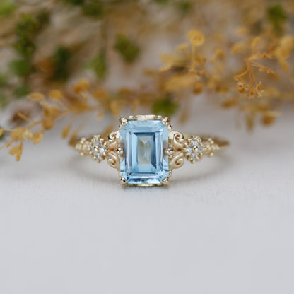 Emerald cut blue gemstone ring set in 18K solid gold with diamond accents and vintage-inspired detailing