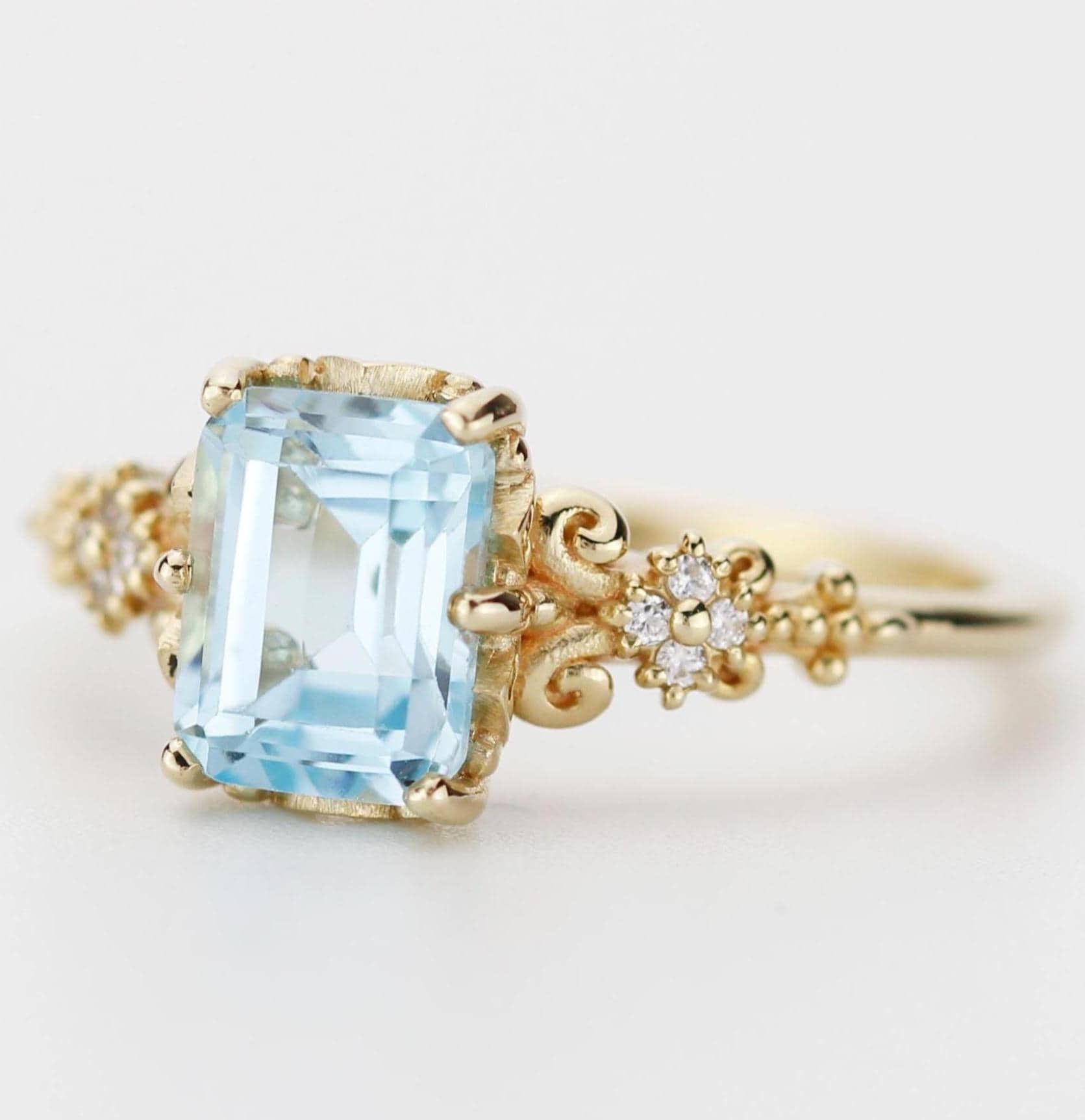Emerald cut blue gemstone ring set in 18K solid gold with diamond accents and vintage-inspired detailing