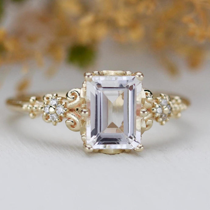 Emerald cut white gemstone ring set in 18K solid gold with diamond accents and vintage-inspired detailing