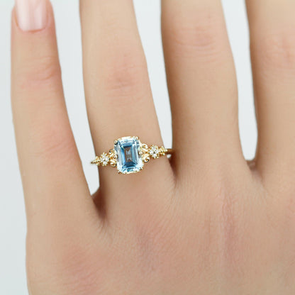 Emerald cut blue gemstone ring set in 18K solid gold with diamond accents and vintage-inspired detailing
