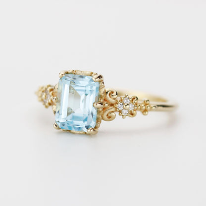 Emerald cut blue gemstone ring set in 18K solid gold with diamond accents and vintage-inspired detailing