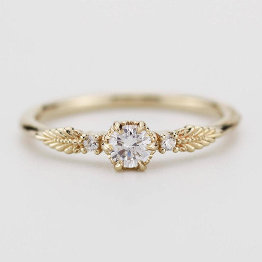 This beautiful vintage engagement ring showcases a round diamond in the center, with two smaller diamonds on the sides. Made from 18k gold, it perfectly blends classic elegance with a modern touch.