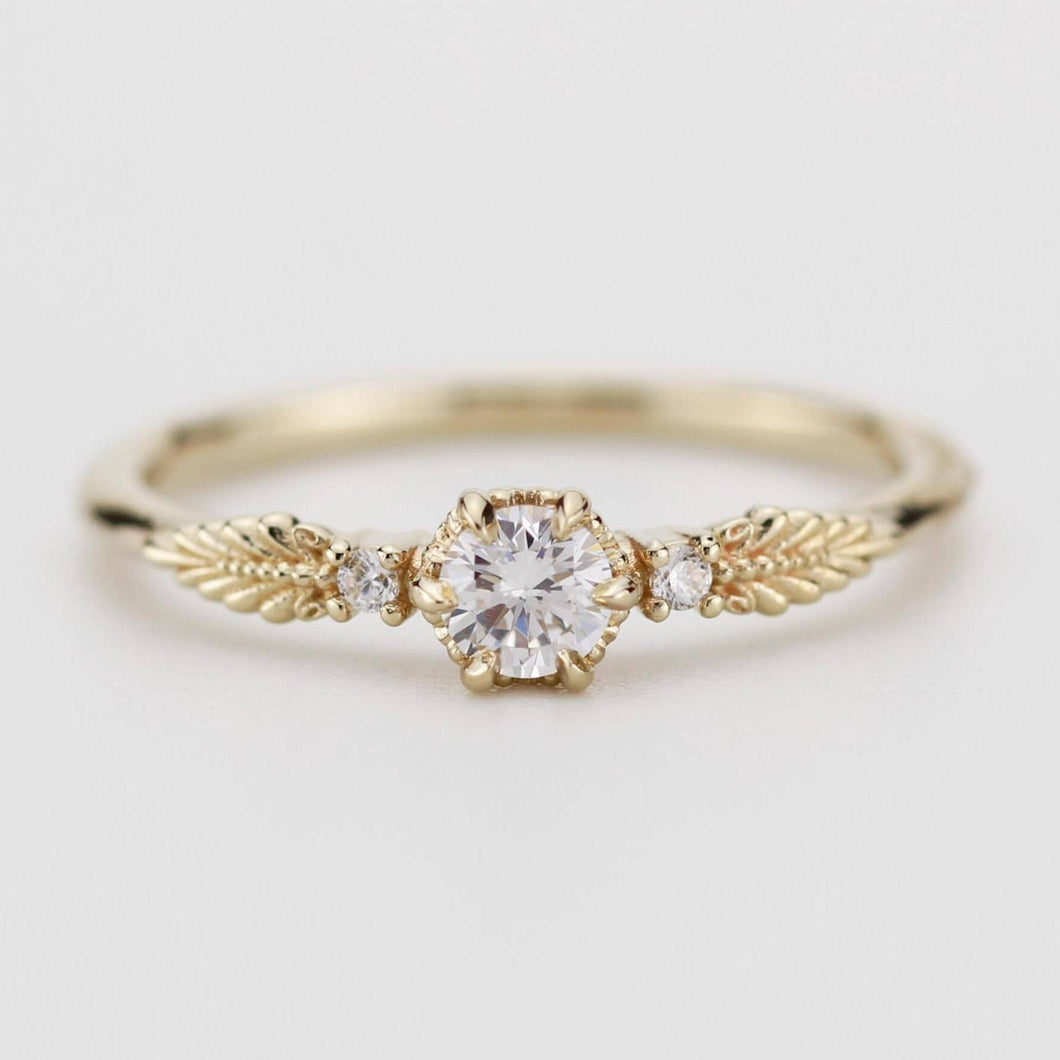 This beautiful vintage engagement ring showcases a round diamond in the center, with two smaller diamonds on the sides. Made from 18k gold, it perfectly blends classic elegance with a modern touch.