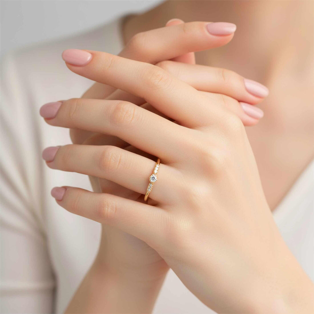 Dainty solid gold ring with a single round diamond center stone framed by six smaller accent diamonds displayed on a hand