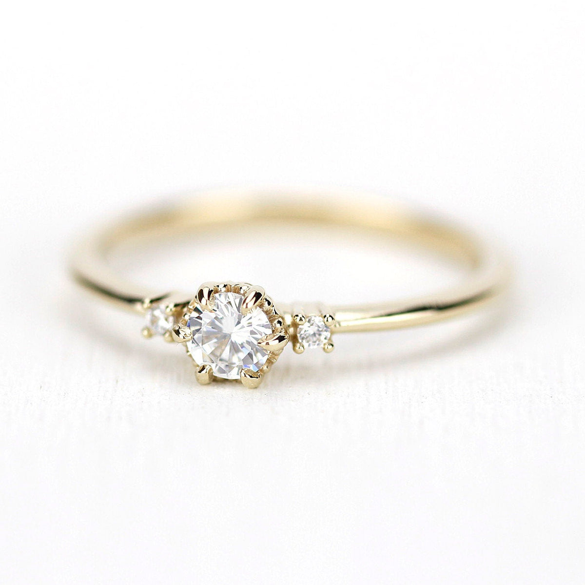 18k gold three stone ring with a round lab grown diamond, angled view