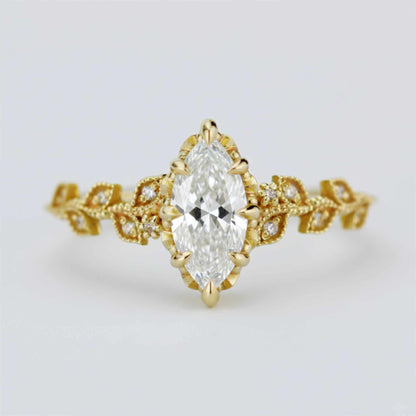 Elegant Nooi Jewelry engagement ring featuring a marquise-cut diamond in a gold setting with intricate leaf-inspired band and delicate pavé diamond accents.