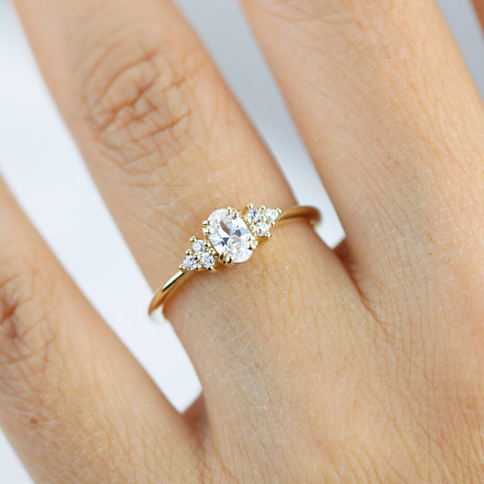 18k gold cluster ring with an oval lab grown diamond, worn on the hand